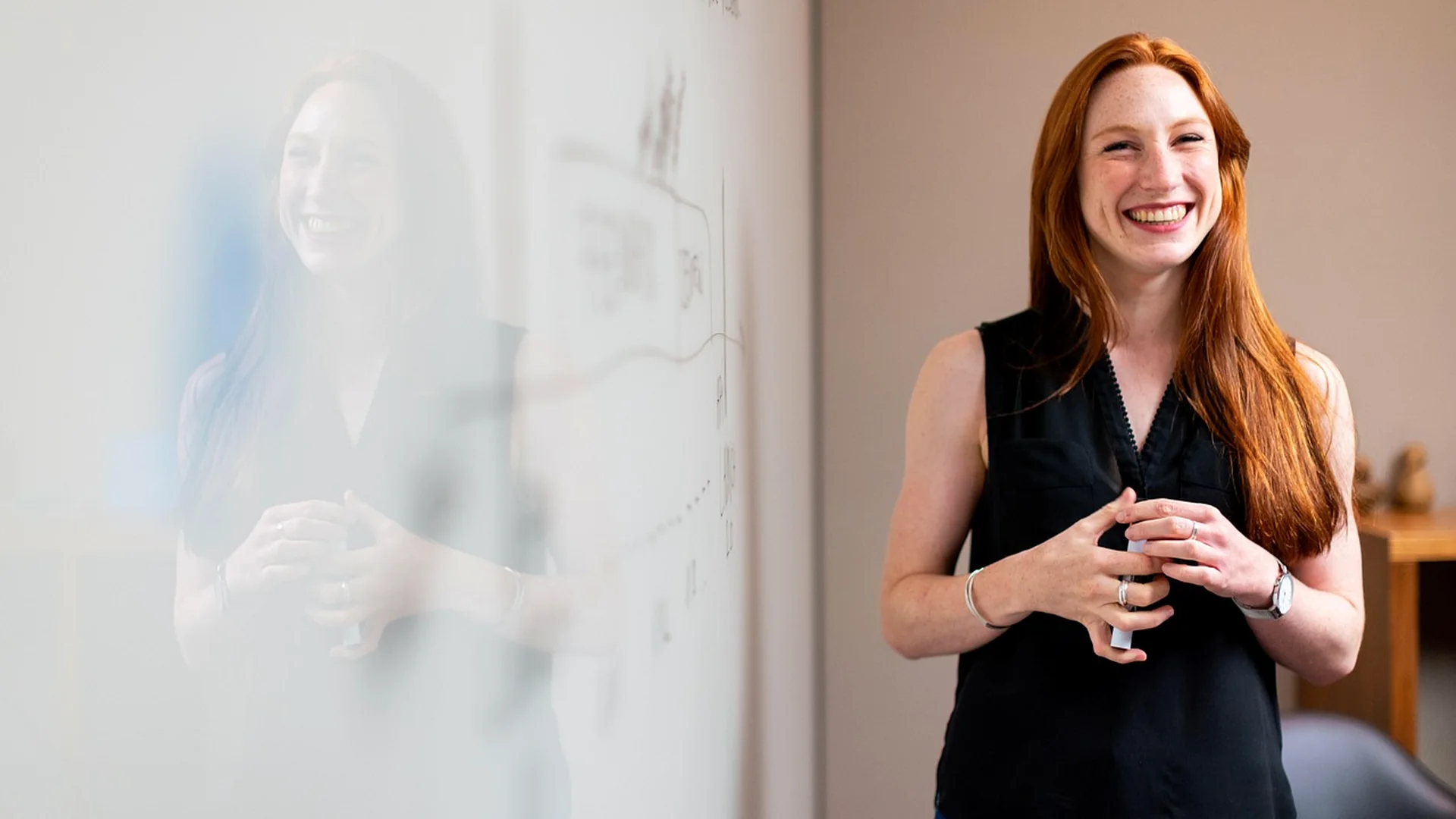 Confident professional woman smiling beside an office whiteboard after CMT exam preparation success